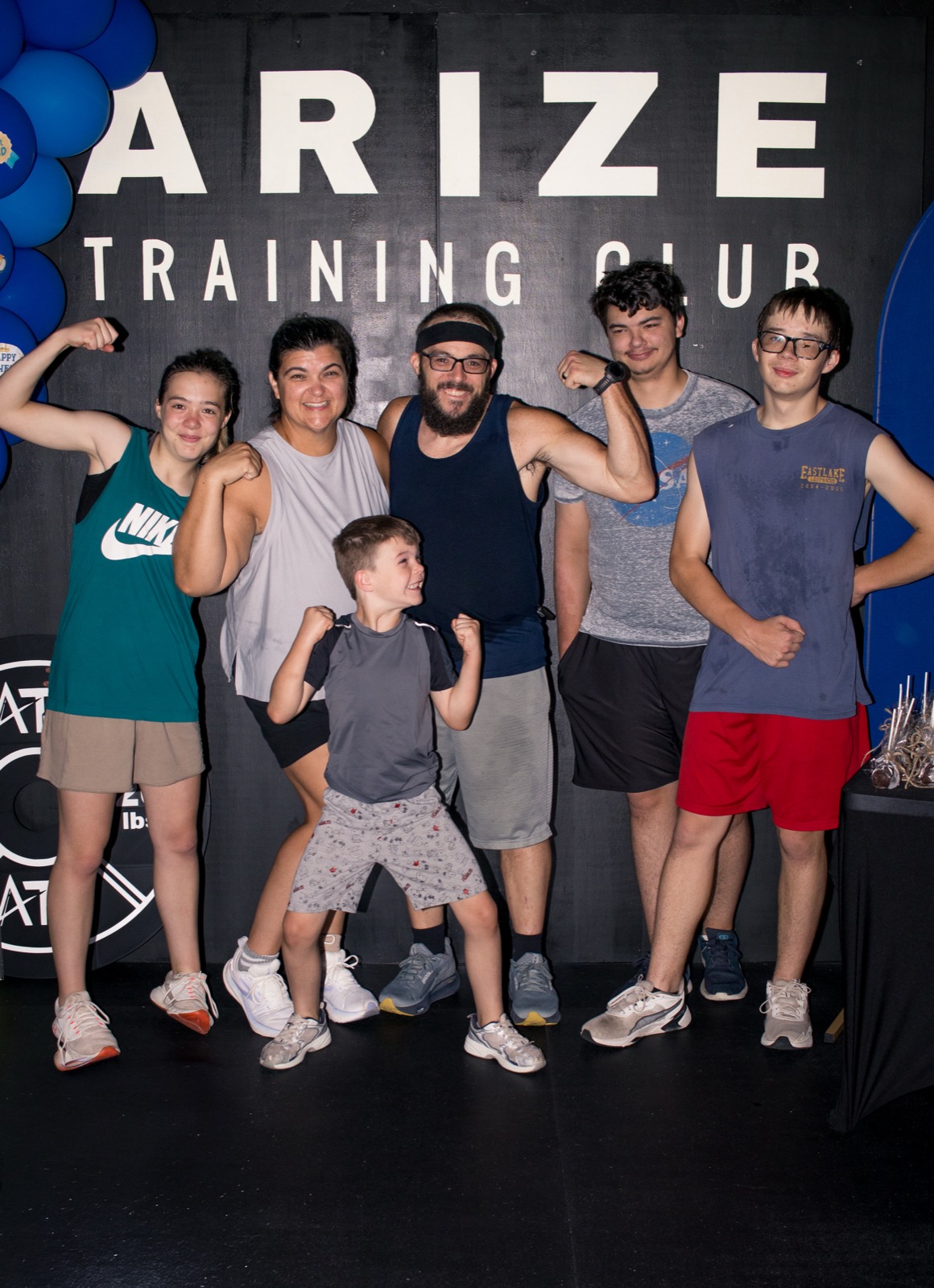 A whole family flexes their arms together at Arize Training Club.